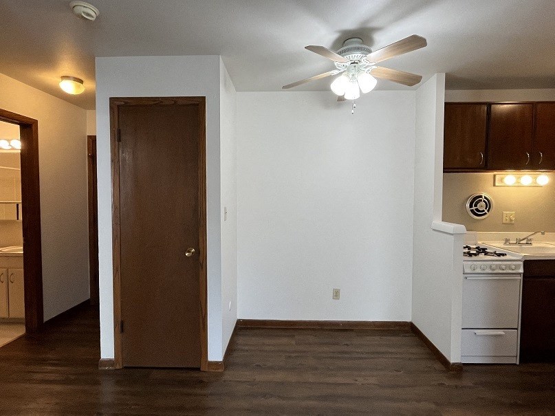 an empty living room with a ceiling fan and a kitchen