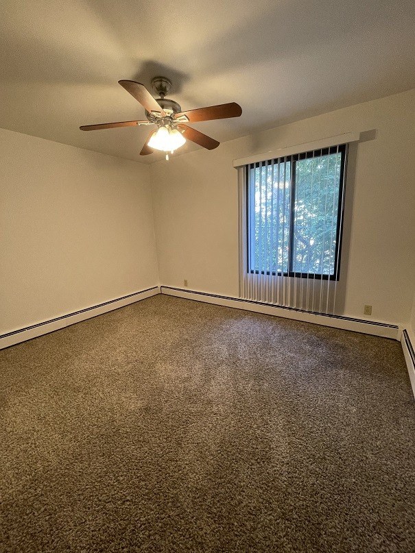 an empty living room with a ceiling fan and a window