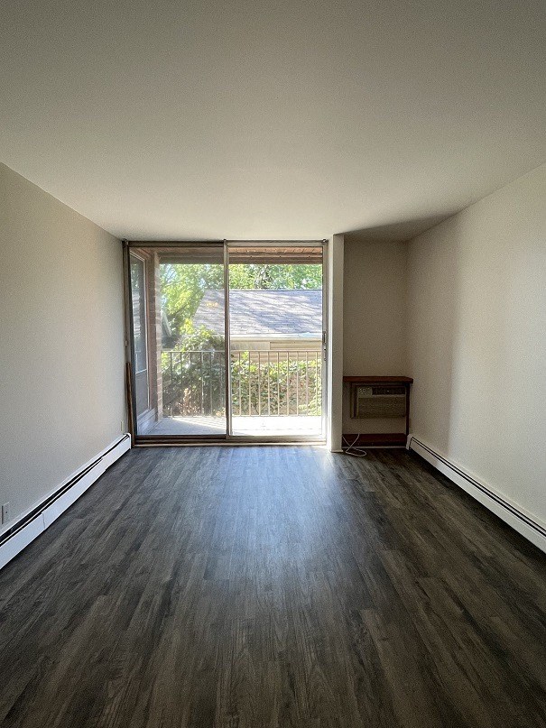 an empty living room with wooden floors and a sliding glass door