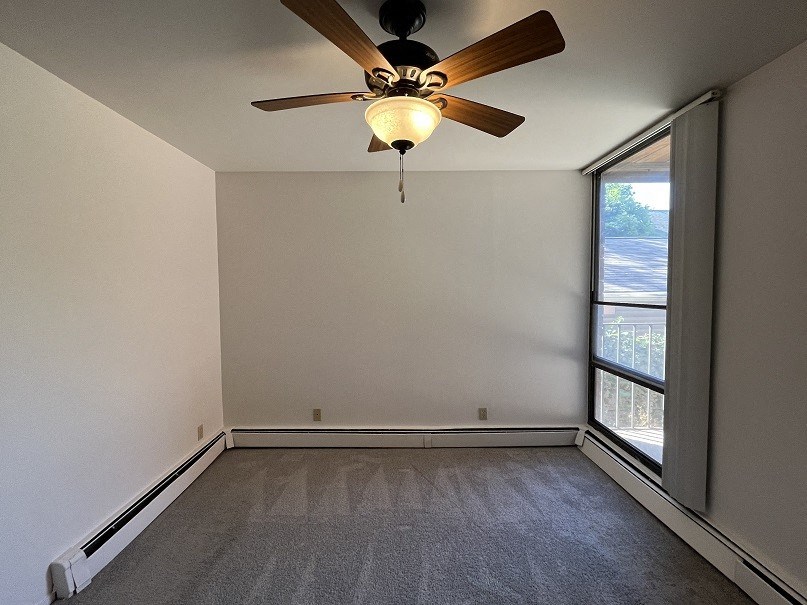 an empty living room with a ceiling fan and a window