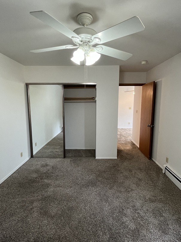 an empty living room with a ceiling fan and a closet