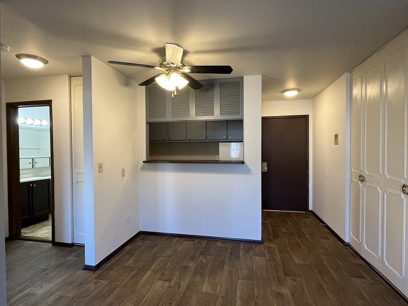 a living room with a ceiling fan and a kitchen