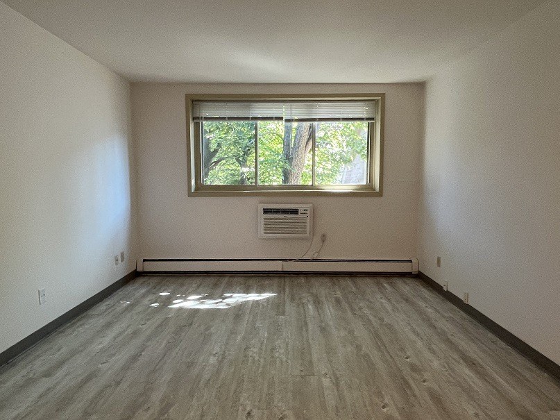 an empty room with a window and wooden floors