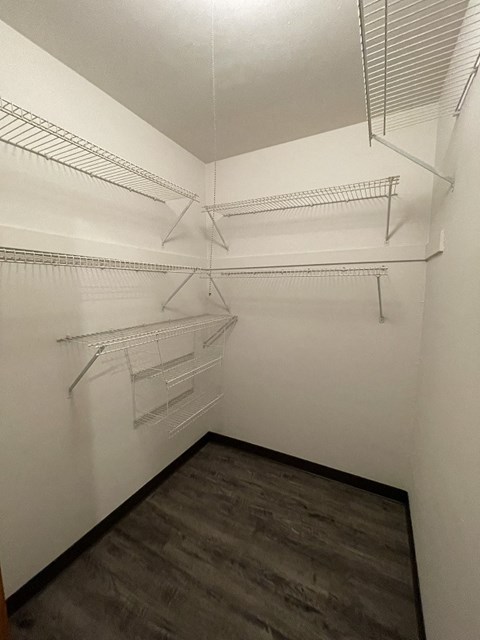 a walk in closet with empty shelves and a hardwood floor