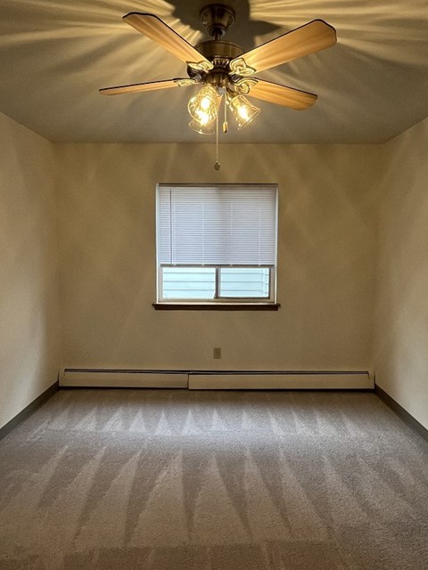 an empty living room with a ceiling fan and a window