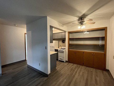 an empty living room with a kitchen and a ceiling fan