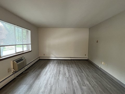 an empty living room with wood floors and a large window