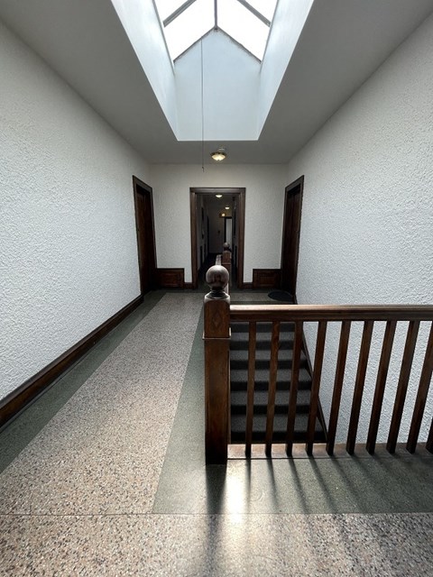a long hallway with a skylight at the top of the stairs