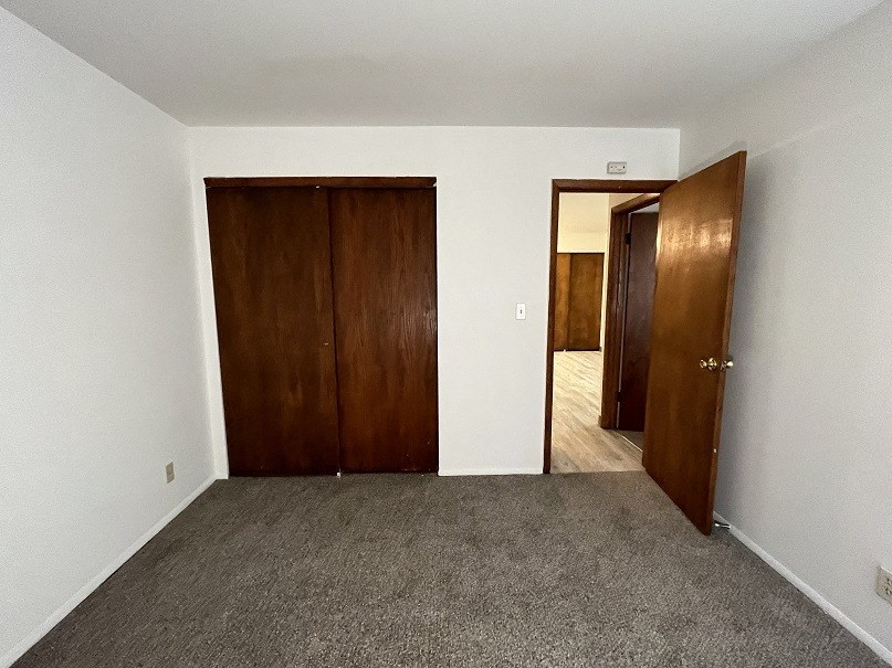 an empty room with two doors and a carpeted floor