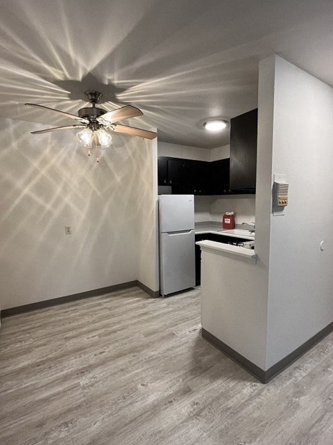 a white kitchen with a ceiling fan and a white refrigerator