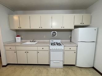 a kitchen with white appliances and white cabinets and a refrigerator