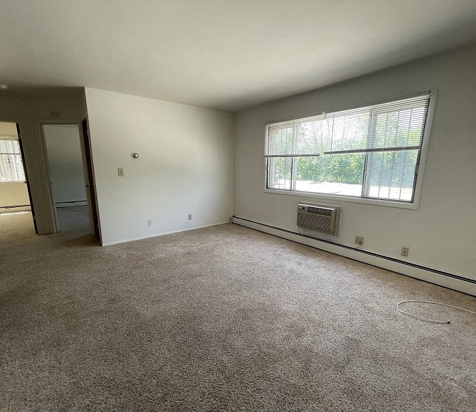 an empty living room with a large window and carpet