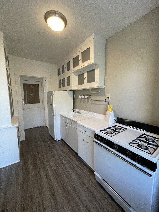 an empty kitchen with white appliances and white cabinets