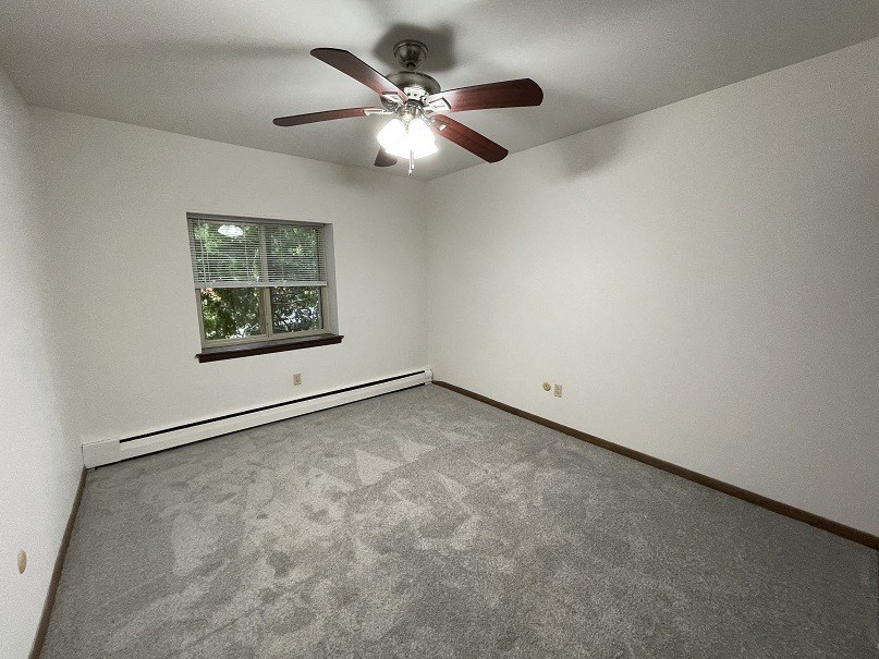 an empty room with a ceiling fan and a window