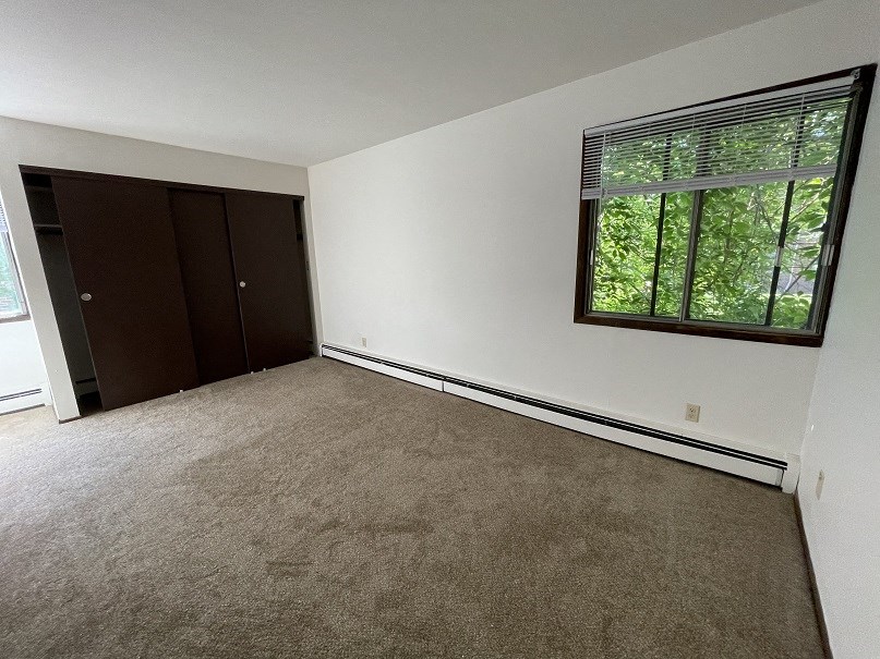 an empty room with a window and a door to a closet