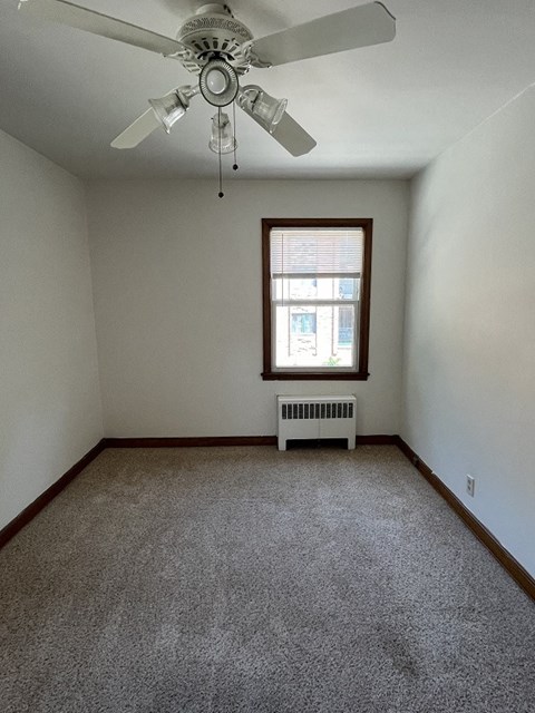an empty room with a ceiling fan and a window
