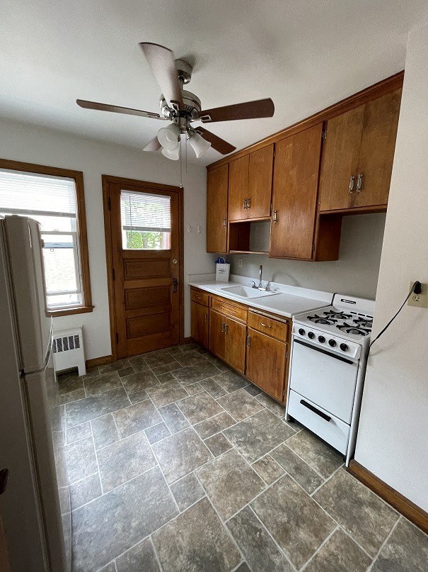 an empty kitchen with a ceiling fan and a refrigerator