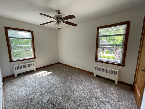 an empty room with a ceiling fan and two windows