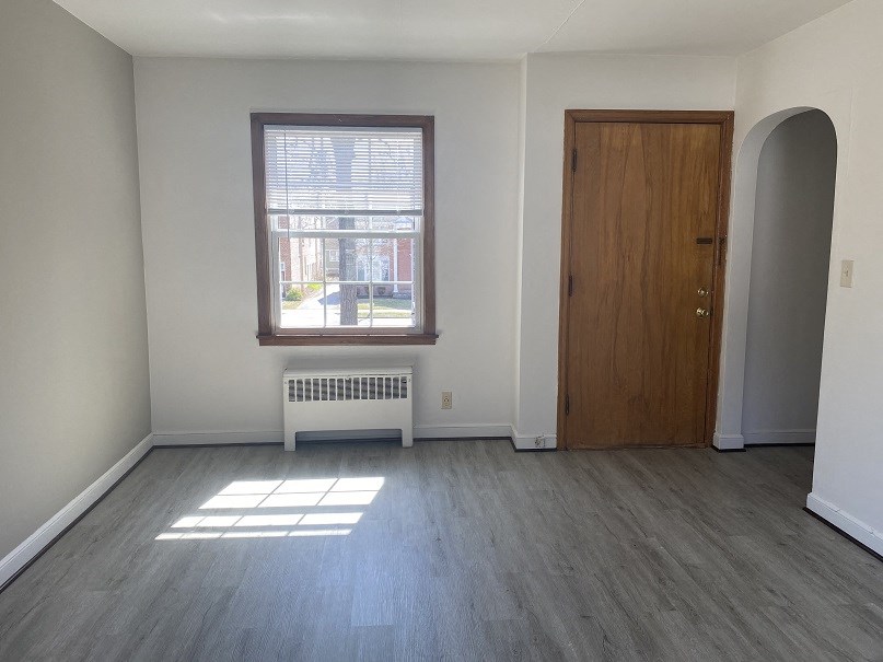 an empty living room with wooden floors and a window