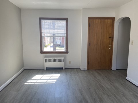 an empty living room with wooden floors and a window