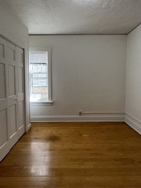 an empty room with a window and wooden floors