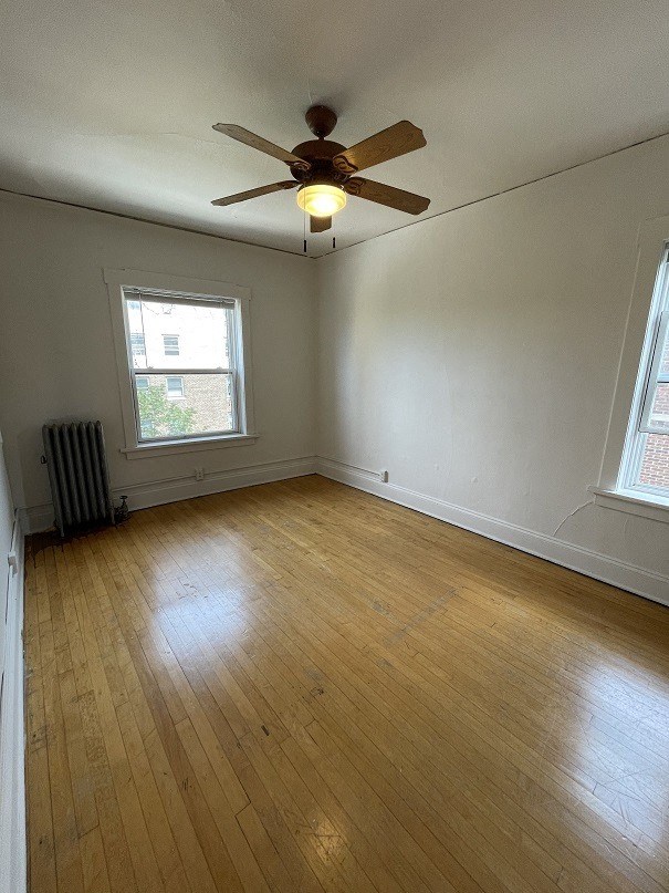 an empty living room with a ceiling fan and wood floors