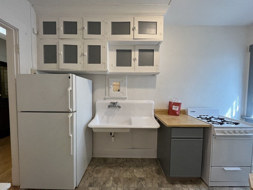 a kitchen with white cabinets and a sink and a refrigerator