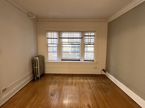an empty room with a window and wooden floors