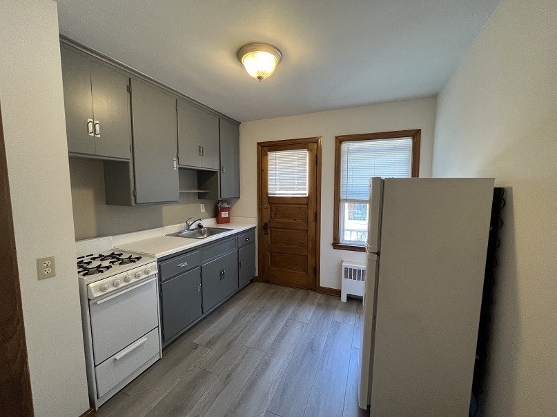 an empty kitchen with white appliances and gray cabinets