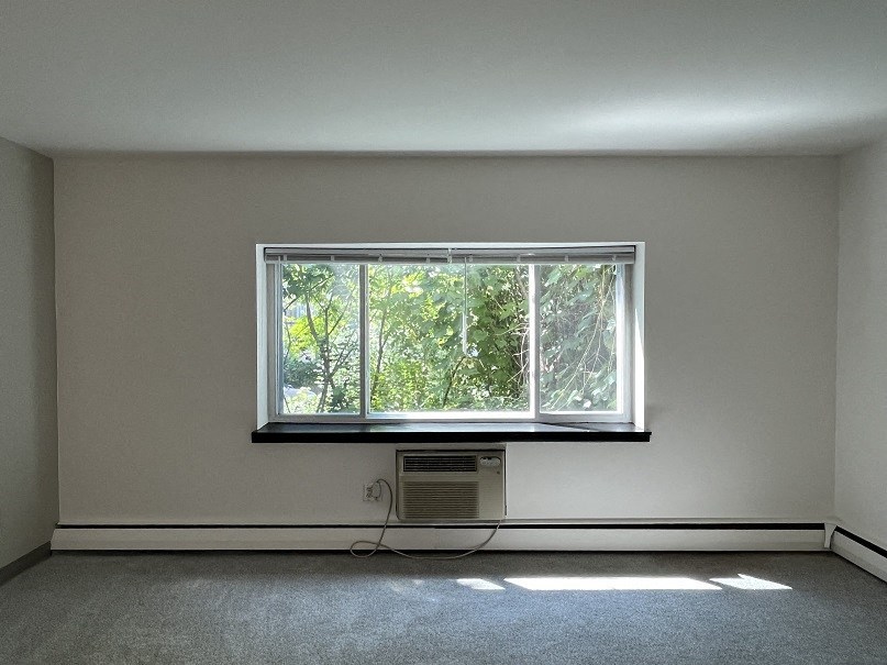 A room with a window and a wall-mounted air conditioner unit.