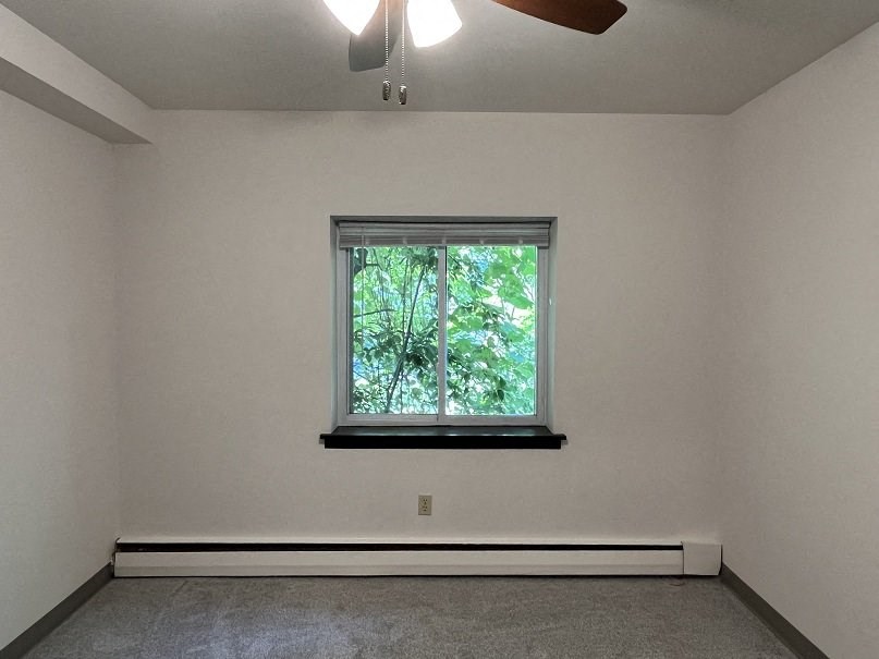 A room with a window and a ceiling fan.