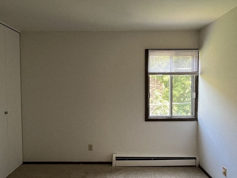 A room with a window and a radiator on the floor.