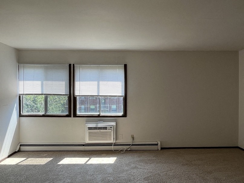 A room with a window and a wall-mounted air conditioner.