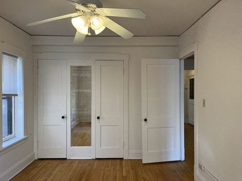 A room with a ceiling fan and wooden floors.
