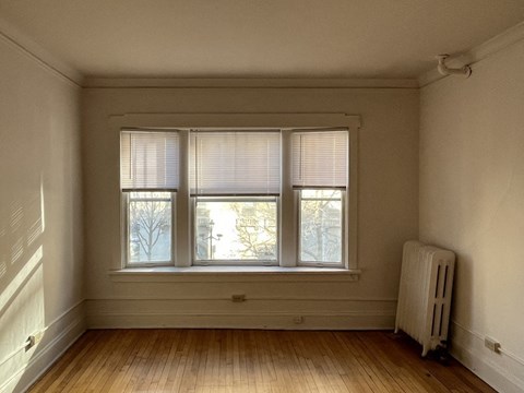 A room with a window and a radiator on the floor.