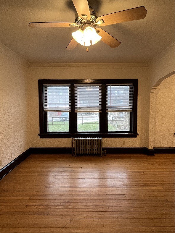 an empty living room with a ceiling fan and a window