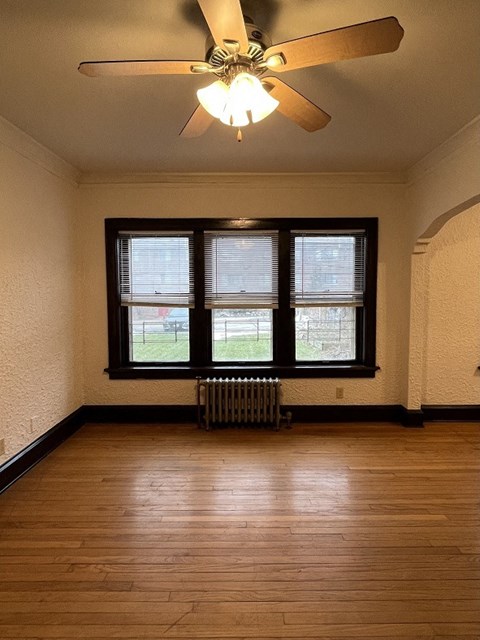 an empty living room with a ceiling fan and a window