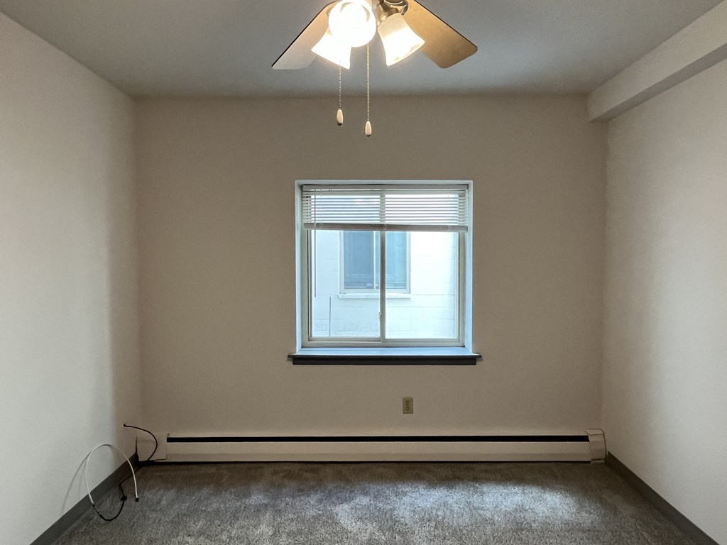 A room with a window and a ceiling fan.