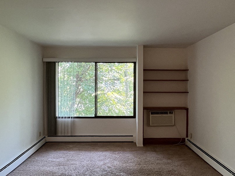 A room with a window and a wall-mounted air conditioner unit.