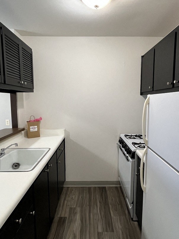 A kitchen with a white sink and black cabinets.