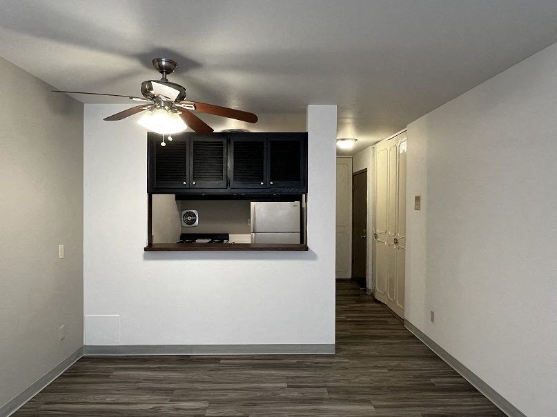 A room with a ceiling fan and a cabinet with a microwave.