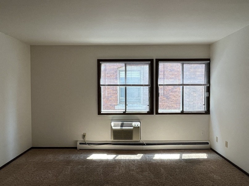 an empty room with two windows and a radiator