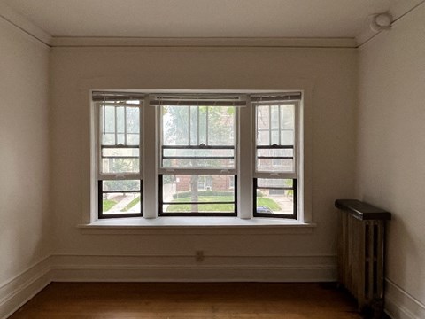 A room with a window and a radiator on the floor.