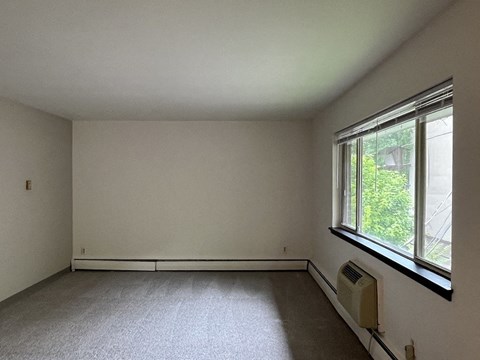 A room with a window and a wall heater.