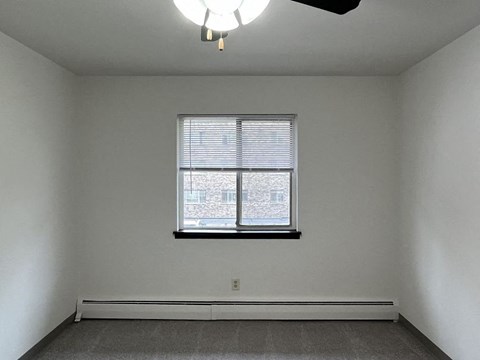 A room with a window and a ceiling fan.