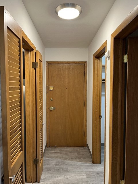 A hallway with wooden doors and a light on the ceiling.