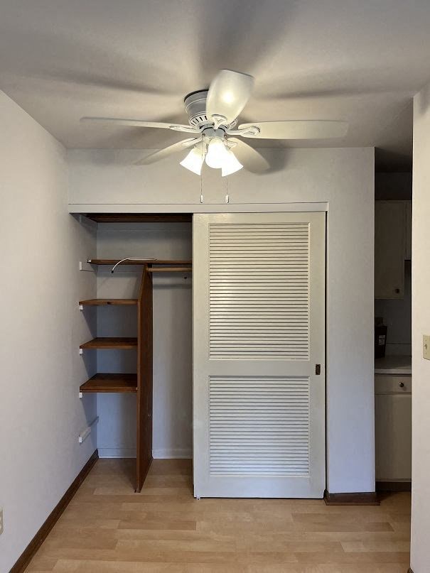 A white ceiling fan hangs over a white door.