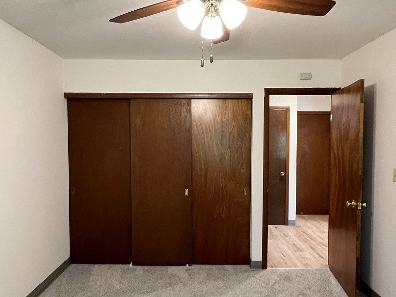 A room with a ceiling fan and two doors.