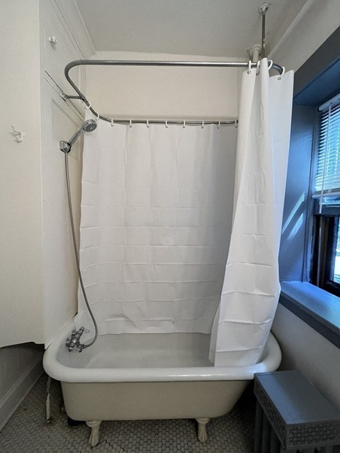A white bathtub with a shower curtain over it.