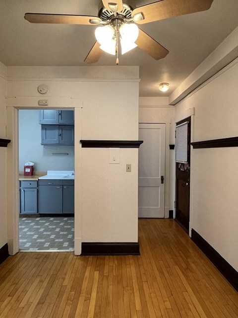 A kitchen with a white wall and a ceiling fan.